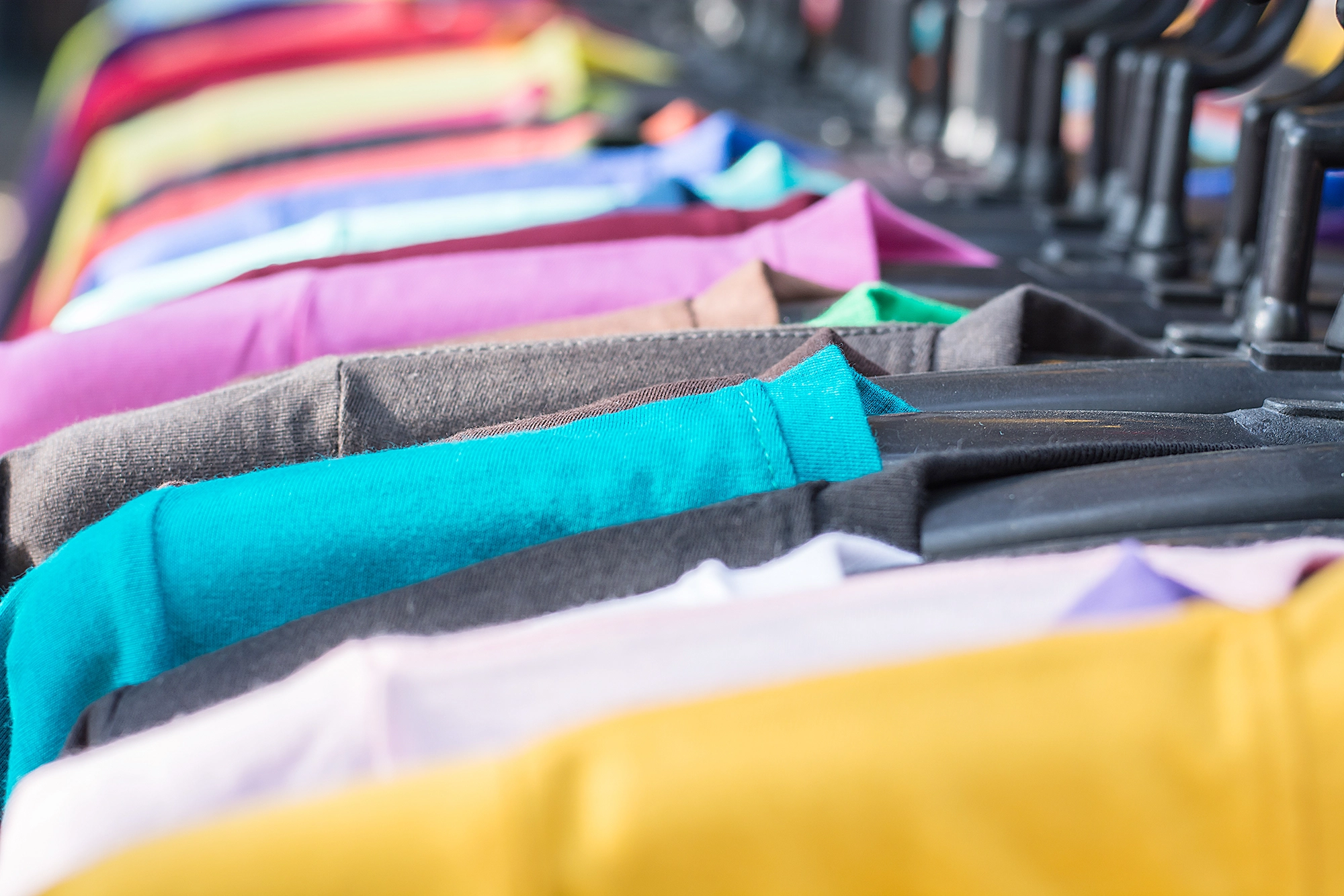 T-shirt promozionali personalizzabili in diversi colori su appendiabiti