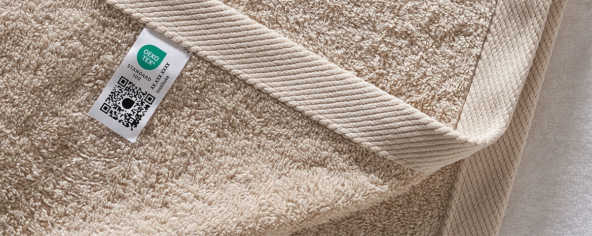 Etichetta OEKO-TEX® STANDARD 100 applicata su tessuto in spugna: certificazione di sicurezza contro sostanze nocive