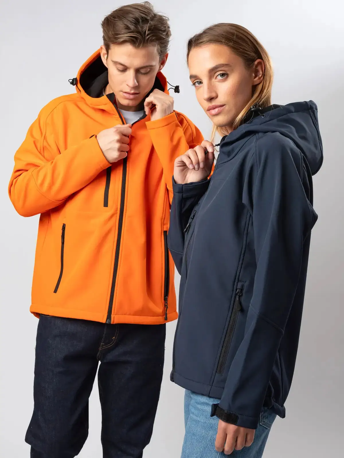Giacca softshell uomo arancione e giacca softshell donna blu navy: esempio di capi tecnici antivento e idrorepellenti