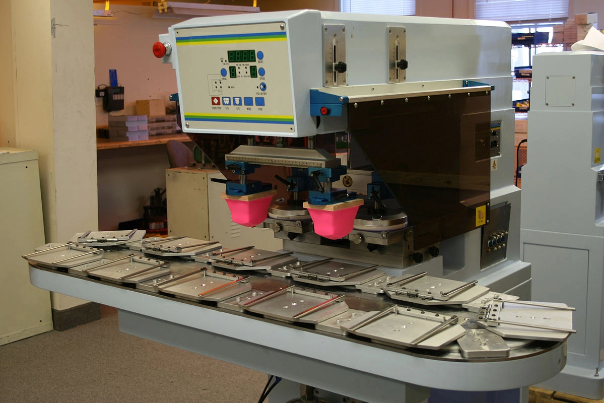 Macchina tampografica a 11 stazioni carousel in funzione, con doppio tampone e piastre di posizionamento.