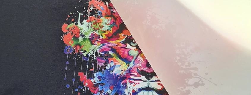 Design colorato trasferito su tessuto con tecnica DTF e film PET in fase di rimozione